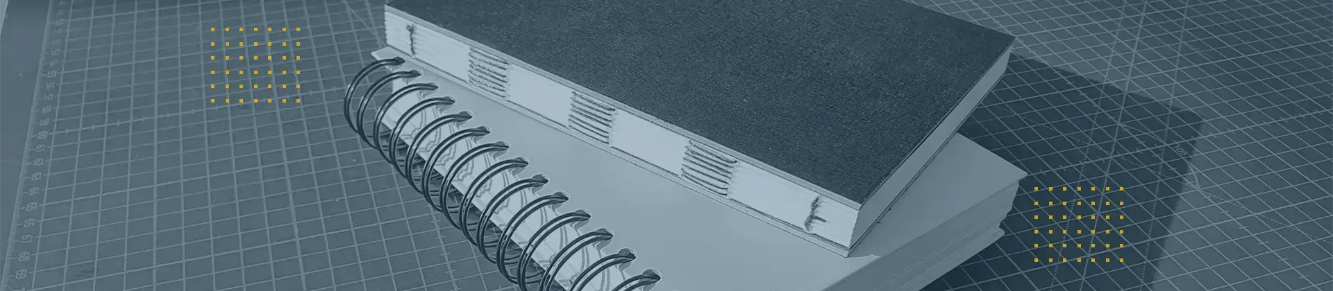 Header-Bild: Gestapelte Bücher zeigen Drahtbindung und offene Fadenheftung; symbolisiert diverse Bindungsoptionen.