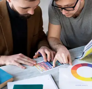 Print consultation: Two colleagues discussing color selection and color schemes using a palette.