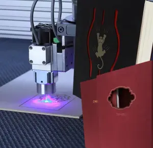 Finishing: A laser cutting machine creates a pattern on wood next to book covers with die-cutting.